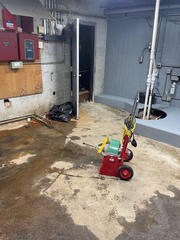Responded to a drain backup emergency where sewage was backing up through the floor drain and flooding the basement utility room. Upon arrival, found significant standing water with sewage covering the concrete floor throughout the space. Extracted standing water from the affected area and assessed the drainage system to identify the source of the blockage causing the backup through the floor drain. Cleared the obstruction in the main drain line to restore proper flow and prevent further sewage backup into the basement.