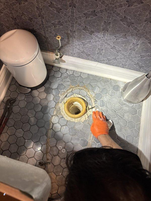 Responded to water damage complaint in basement ceiling below bathroom. Upon inspection, removed toilet to access flange area and identified failed wax ring seal as source of leak. Water infiltration had occurred at toilet base, seeping through floor and causing visible ceiling damage below. Replaced deteriorated wax ring with new seal, reinstalled toilet with proper compression, and tested flush cycles to confirm watertight seal and proper drainage.