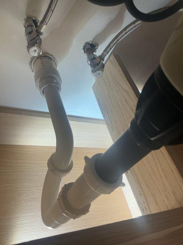 Responded to service call for sewer camera inspection, slow-draining kitchen sink, and gurgling sounds in bathroom plumbing. Performed comprehensive visual inspection of bathroom vanity plumbing system, including P-trap assembly, supply lines, and drain connections. Documented existing plumbing configuration with white PVC drain components and braided stainless steel supply lines in proper working order. Inspected under-sink plumbing for potential drainage issues and verified trap installation to address reported gurgling concerns.