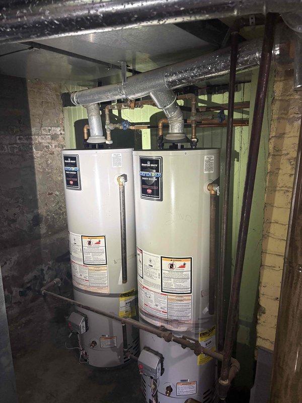 Conducted on-site evaluation for replacement of existing 40-gallon Bradford White gas water heater in basement mechanical room. Assessed current installation featuring dual water heater configuration with overhead gas piping, flexible ductwork, and venting system. Documented existing conditions including water heater placement, gas line connections, exhaust venting arrangements, and clearance requirements within unfinished basement space with concrete block walls and exposed structural elements. Provided estimate for removal of old unit and installation of new standard tank-style gas water heater with proper venting and code-compliant connections.