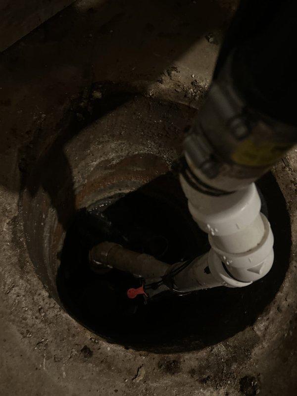 # Drain and Sewer Estimate Commercial

Conducted a comprehensive assessment of a commercial sump pump system located in a basement utility area. The inspection revealed an aging sump pump installation with a cylindrical concrete basin containing dark water, deteriorating floor conditions, and visible surface staining indicating potential moisture management issues. Evaluated the existing pump mechanism, white PVC discharge piping, electrical connections, and associated backup power equipment including a StormCell battery backup system with digital monitoring display showing operational status at 147 volts. Documented equipment configuration, wiring conditions, and overall system performance to provide detailed estimates for potential repairs, upgrades, or complete system replacement to ensure reliable drainage protection for the commercial facility.