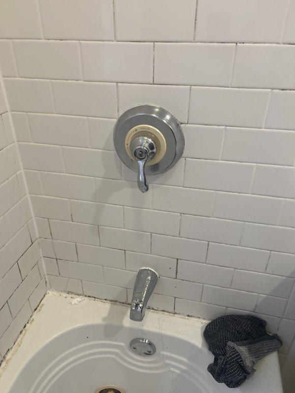 Responded to service call for reported shower head leak in bathroom. Upon arrival, contacted customer as requested and inspected the shower assembly. Examined chrome shower faucet fixture, tub spout, and surrounding white subway tile installation. Noted discoloration and staining along caulk line at tub-to-tile junction indicating moisture intrusion. Assessed plumbing connections and water supply lines. Completed necessary repairs to eliminate leak source. Verified proper operation of shower fixtures and confirmed no additional water seepage. No building-wide water shutoff was required for this repair.