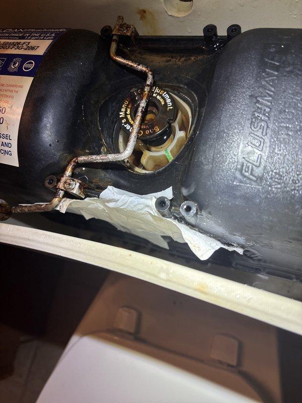 Inspected and assessed water heater system experiencing significant corrosion on metal piping and connections. Documented heavily deteriorated tubing assembly at top of pressure vessel showing extensive rust and oxidation damage. Evaluated condensate pump assembly and drain pan condition, noting moisture accumulation and sediment buildup in collection system. Provided photographic documentation of corroded components and recommended replacement of affected piping to prevent potential system failure and water damage.