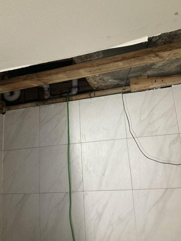 Completed bathroom re-pipe installation with new PVC piping system. Removed existing plumbing infrastructure and installed replacement supply lines and drain piping throughout the bathroom area, including proper connections at ceiling joists and structural framing members. All PVC joints were properly primed and solvent-welded per code requirements, with purple primer visible at all connection points to ensure quality assurance documentation.