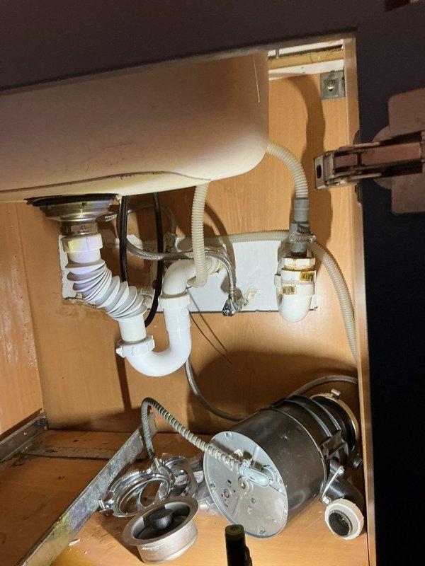 Installed new garbage disposal unit under kitchen sink, including complete mounting assembly and connection to existing drain system. Configured PVC P-trap drainage with proper venting, connected water supply lines with shut-off valves, and tested all connections for leaks to ensure proper operation of the disposal unit and drainage system.