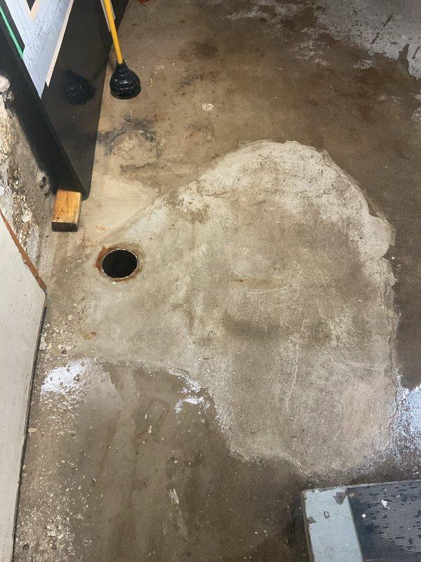 Responded to residential main sewer drain blockage in basement. Successfully cleared clog in main line running from basement cleanout to street connection using mechanical drain cleaning equipment. Accessed drain through basement floor cleanout, deployed cable snake through line to remove obstruction and restore proper flow. Tested system to confirm full drainage restored. Basement floor drain and surrounding area showed evidence of previous backup with water staining on concrete floor. No structural damage to drain system observed; cleanout cover and access point remain functional. Advised customer that drainage is operating normally.
