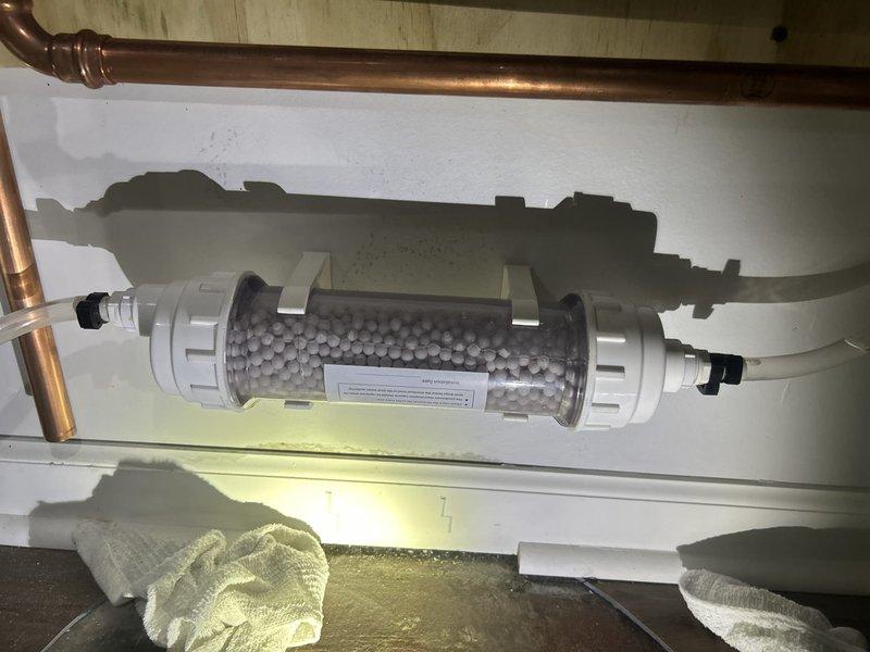 Responded to emergency call for water heater leak in basement. Upon arrival, assessed the situation and documented the existing HVAC and plumbing infrastructure, including water filtration system with visible staining on mounting surfaces indicating potential water damage. Photographed equipment configuration and drainage lines for service records.