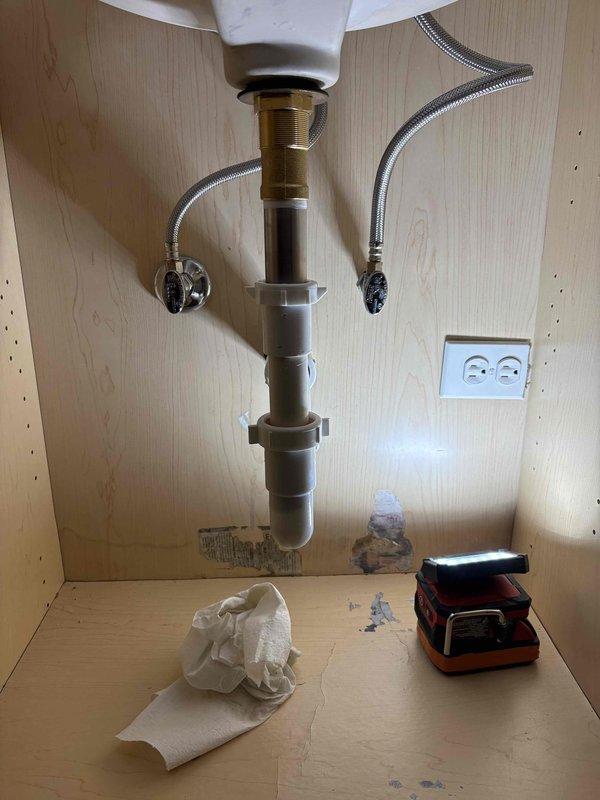 Replaced bathroom sink faucet assembly with new three-handle chrome fixture featuring separate hot and cold cross-handle taps and central spout. Installed new drain assembly and P-trap, connected supply lines to shut-off valves, and verified proper operation with no leaks detected.