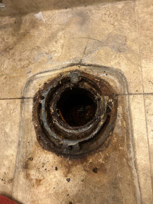 Responded to water leak investigation request from property below affected unit. Conducted visual inspection of bathroom floor drain and surrounding area to assess potential leak source. Documented heavily corroded floor drain fixture with extensive rust deterioration and mineral deposit accumulation on metal rim and interior surfaces. Observed significant water staining and discoloration patterns radiating outward from drain on tile flooring, indicating prolonged moisture exposure. Photographed corroded drain assembly and deteriorated grout lines for estimate preparation. Identified aged plumbing fixture requiring replacement due to advanced corrosion compromising drain integrity. Coordinated with upstairs residents to schedule follow-up estimate for necessary repairs.