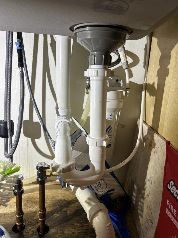 Responded to kitchen sink drain leak. Upon inspection, identified compromised slip-joint connections in the PVC P-trap assembly beneath the sink. Disassembled drain system, cleaned all mating surfaces, and reinstalled P-trap with new washers and proper alignment. Tightened all compression fittings to manufacturer specifications. Tested system under full water flow to verify leak elimination. All plumbing components now functioning properly with no active leaks detected.