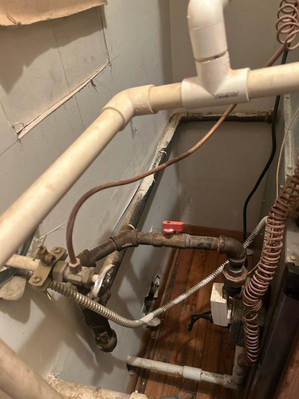 Performed initial assessment and sold repair for dryer vent installation project. Documented existing plumbing infrastructure including mixed-age components with white PVC piping, copper coiled tubing, metal fittings, and flexible conduits in utility space. Inspected hot and cold water shut-off valves with red wheel handles mounted in recessed wall access panel. Job remains incomplete pending customer scheduling for final phase, which involves coring hole through exterior wall and completing dryer vent installation and termination.