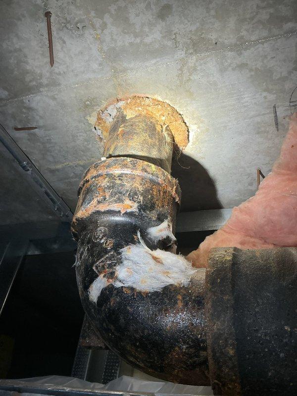Responded to water intrusion concerns and conducted thorough plumbing inspection of exposed piping system through ceiling access point. Upon arrival, homeowner had already opened ceiling to investigate water staining and requested detailed assessment of plumbing infrastructure condition.

Inspection revealed severely corroded cast iron pipe system with extensive deterioration throughout visible sections. Primary findings included a 90-degree elbow joint exhibiting advanced rust coverage with orange, brown, and black corrosion patterns across entire surface. Metal showed significant flaking, surface degradation, and complete failure of original protective coating in multiple areas. Corrosion was most pronounced on curved elbow section where metal substrate was exposed beneath deteriorated coating layers.

Additional piping visible through ceiling opening displayed similar rust patterns and surface deterioration, indicating systemic corrosion issues rather than isolated failure. The adva