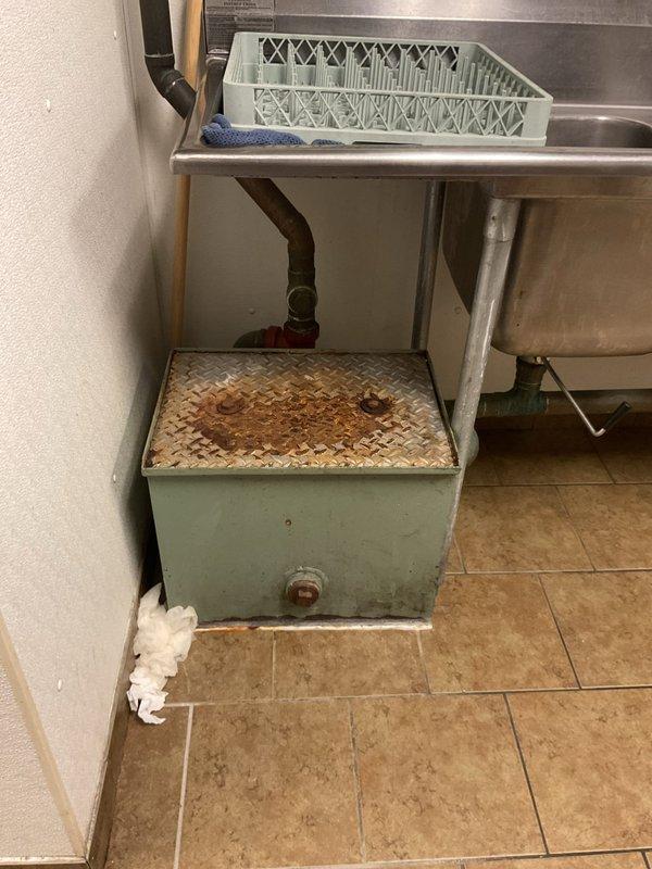 Responded to commercial kitchen plumbing service call where inspection revealed significant corrosion on utility infrastructure and mechanical systems. Documented deteriorated conditions including heavily rusted step platform beneath commercial sink area and corroded valve fittings on suspended tank piping system in mechanical room. Assessed oxidized galvanized steel pipes, weathered connection points, and aging plumbing components showing mineral deposits and advanced corrosion throughout the installation.
