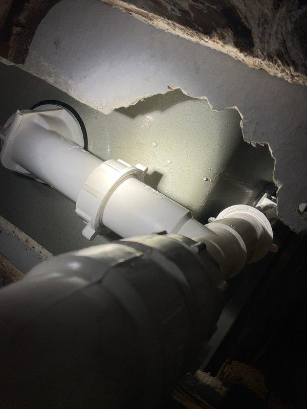 Responded to warranty callback for recurring bathtub leak previously repaired. Upon inspection, discovered failed P-trap assembly with active water infiltration causing extensive damage to surrounding drywall and structural components. Removed deteriorated trap, replaced with new PVC P-trap assembly and connections, repaired water-damaged wall section, and verified proper drainage with no leaks detected upon completion.