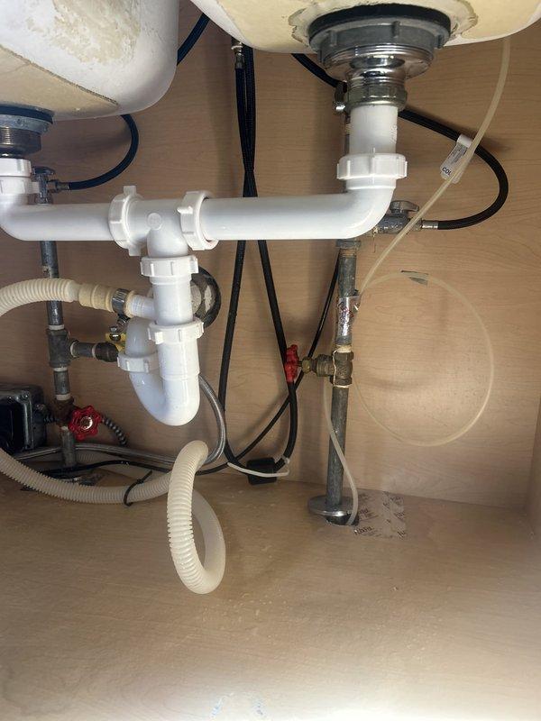 Responded to kitchen sink leak originating from beneath the fixture. Upon inspection, identified compromised connection at the tailpiece assembly where water was escaping during use. Tightened drain connections and replaced worn slip joint washers on the P-trap assembly to restore proper seal. Additionally, addressed slow-draining shower by clearing obstruction in the drain line that had prevented effective snaking, restoring normal water flow.