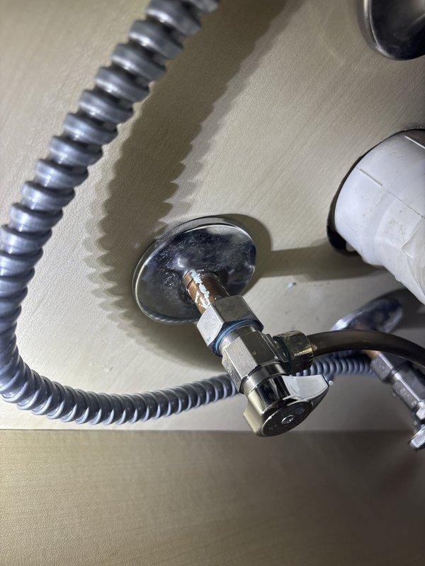 Responded to service call for water leak beneath kitchen sink. Upon inspection, identified leak originating from compression fitting at supply line connection. Tightened compression nut and verified proper seal at escutcheon plate mounting point. Tested system under full water pressure and confirmed leak was successfully eliminated. All plumbing connections restored to proper working condition with no further seepage detected.