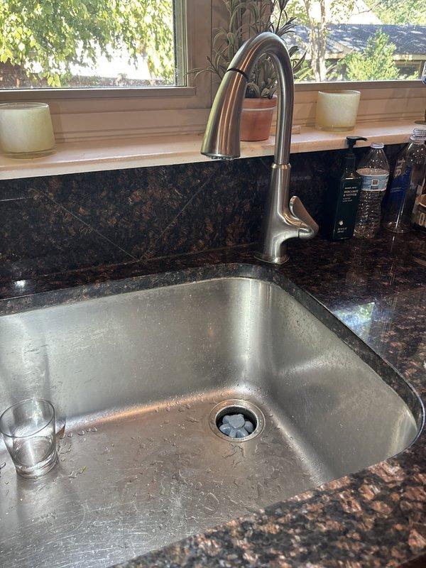 Responded to service call for water leak beneath kitchen sink. Upon inspection, identified leak originating from compression fitting at supply line connection. Tightened compression nut and verified proper seal at escutcheon plate mounting point. Tested system under full water pressure and confirmed leak was successfully eliminated. All plumbing connections restored to proper working condition with no further seepage detected.