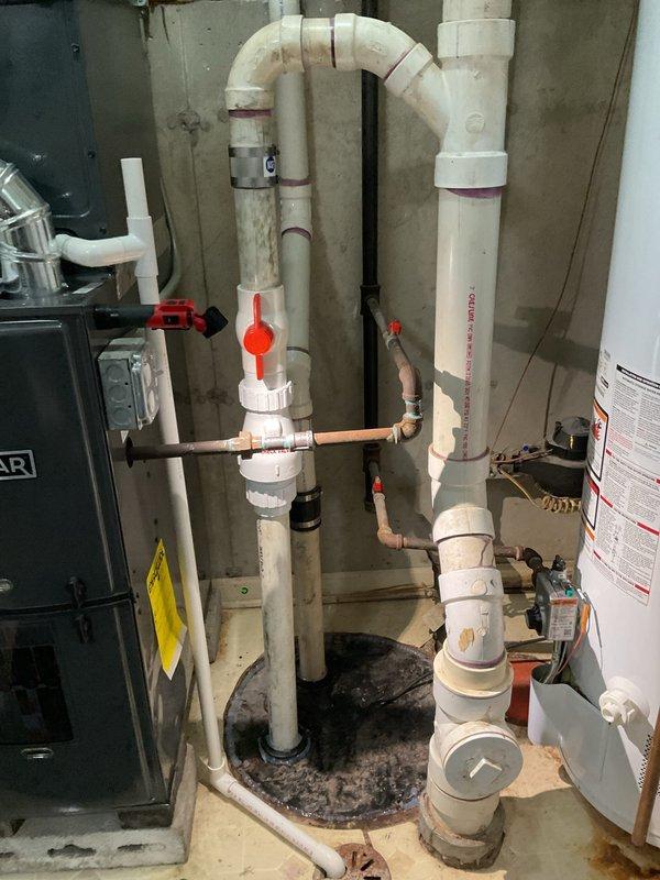 Responded to basement flooding complaint in utility closet following heavy rainfall. Performed comprehensive inspection of sump pump system, drainage pit, and associated plumbing components. Identified muddy water residue and dark staining around sump pit perimeter indicating recent water accumulation. Examined PVC discharge piping, check valve operation, and electrical connections to pump unit. Verified proper pump installation, float switch functionality, and drainage system integrity. Assessed HVAC equipment proximity and potential water intrusion points. Documented existing conditions including residue buildup along floor seams and utility closet surfaces.