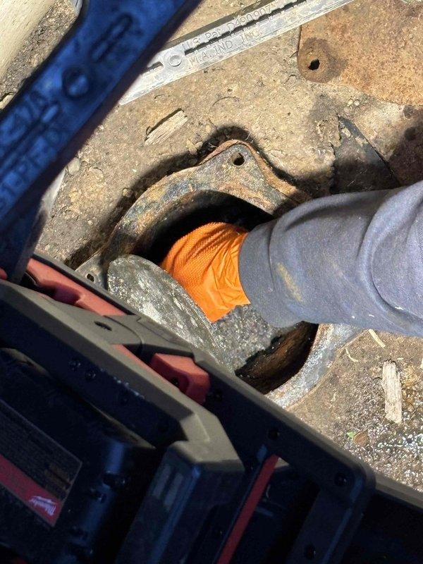 Performed comprehensive flood control inspection utilizing camera equipment from both the interior cleanout access point and the flood control system itself. Accessed and inspected corroded metal piping and fittings through concrete surface openings, documenting condition of aged infrastructure components showing significant rust and deterioration. Verified installation status and operational integrity of existing flood control system.