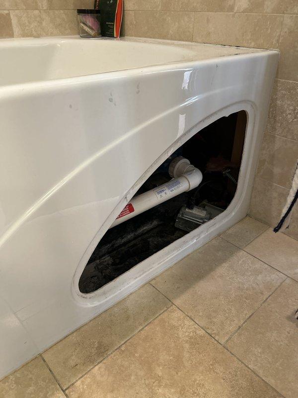 Responded to customer concern regarding potential water leak from shower or bathtub area. Accessed plumbing components through bathtub access panel to inspect water heater connections, supply lines, and drain assembly. Documented mechanical equipment condition and visible plumbing infrastructure for leak assessment and further evaluation.