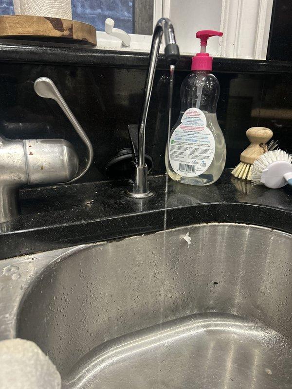 Inspected and documented existing under-sink three-stage water filtration system consisting of sediment filter, carbon block filter, and reverse osmosis membrane. System is properly mounted and operational with all filter canisters securely connected via white tubing and fittings. Verified installation serves kitchen sink with chrome faucet on black granite countertop. All components functioning as designed with no visible leaks or issues detected.