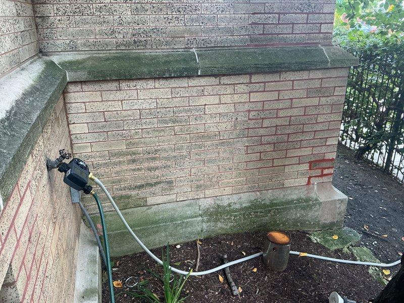 Responded to basement water intrusion complaint occurring during rain events. Conducted comprehensive leak location assessment of exterior porch area and interior drainage system. Inspection revealed exterior brick wall showing significant weathering, algae growth, and compromised coping stones allowing water penetration. Interior investigation identified improperly installed or disconnected floor drain with no functional connection to drainage system, resulting in water discharge directly onto basement floor. Documented conditions with photographic evidence showing exterior water entry points at porch perimeter and interior ductwork/drainage components. Identified dual water intrusion sources: exterior envelope failure at porch interface and deficient interior drain installation. Provided diagnostic findings to clarify conflicting assessments from previous contractors.