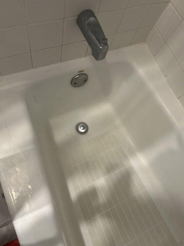 Responded to report of water leak from ceiling near bathroom area. Conducted thorough visual inspection of bathroom fixtures, plumbing connections, and surrounding areas to locate source of moisture intrusion. Examined toilet, vanity plumbing, bathtub/shower assembly, and all visible supply and drain lines. Inspected tub spout, faucet assembly, overflow plate, and drain connections for signs of active leaking or water damage. Documented conditions with photographs for service records. Bathroom currently out of service pending leak resolution.