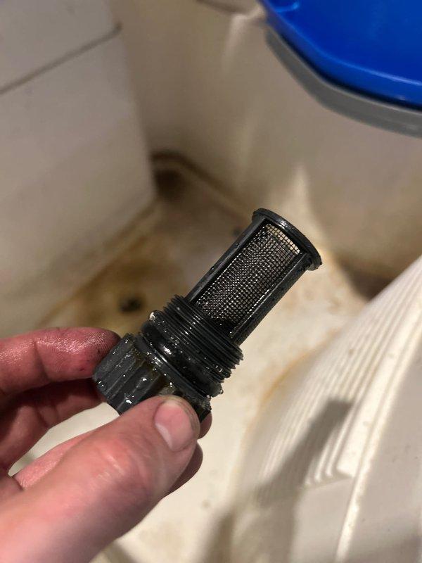 Performed annual maintenance inspection on tankless water heater system. Removed and cleaned inlet water filters, which showed debris accumulation on mesh screens. Inspected both black cylindrical inlet filter and white circular strainer filter, cleared blockages, and reinstalled components to ensure optimal water flow and system performance.