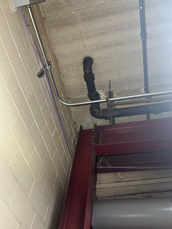 Responded to water leak location service for 6-inch drain pipe leaking from ceiling to floor in commercial facility. Documented ceiling-mounted drainage infrastructure including black insulated piping, metallic drain lines, and associated fittings in unfinished concrete ceiling space. Photographed leak source area and surrounding mechanical systems for assessment and repair planning.
