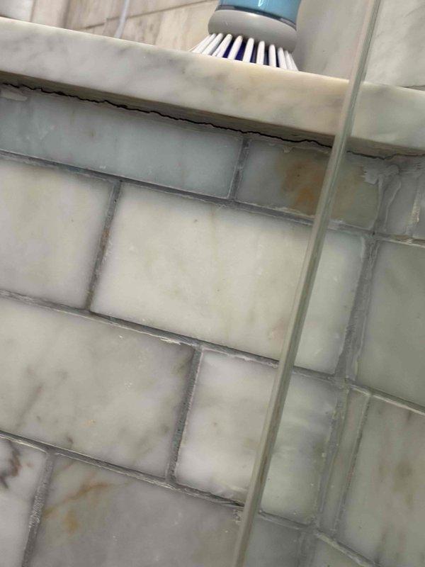 Responded to leak location request for water intrusion from upper unit shower affecting apartment below. Performed thorough inspection of shower enclosure, examining tile walls, grout lines, and fixtures to identify source of leak. Inspected subway tile surround and grout integrity, noting areas of discoloration and potential water penetration points. Documented condition of tile installation, grout lines, and shower shelf area where water may be bypassing waterproofing membrane. Identified compromised grout and potential failure points in tile surround that could allow water migration through wall assembly into unit below.