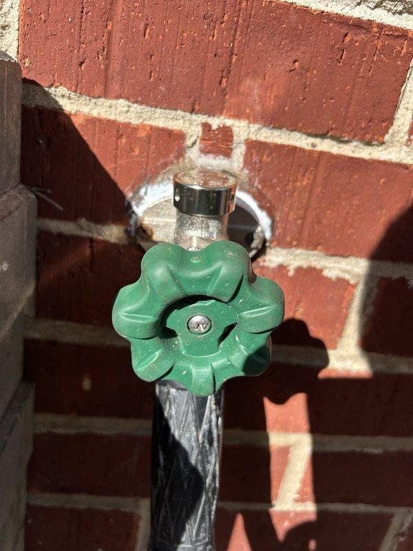 Responded to exterior hose bib leak at brick building foundation. Upon inspection, found recently replaced hose bib was loose at wall connection point, causing water seepage on exterior side of mounting location. Tightened mounting hardware, resealed connection point between spigot and brick wall penetration, and tested for proper operation and water-tight seal under pressure.