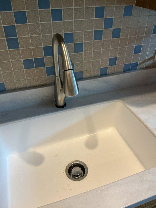 Successfully removed existing kitchen faucet and installed new customer-provided brushed stainless steel faucet with single-handle operation. Disconnected water supply lines from previous fixture, removed old mounting hardware from undermount sink configuration, and prepared mounting surface on light-colored quartz countertop. Installed new faucet assembly with proper sealing, connected braided metal supply lines to hot and cold water valves, and verified secure mounting to prevent movement. Tested water flow and checked all connections for leaks, confirming proper operation of new fixture. All plumbing connections under cabinet are secure with no drips detected.