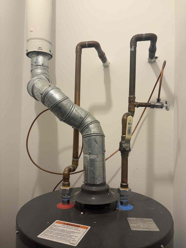Responded to no hot water complaint on newly installed tank water heater in basement. Upon arrival, inspected unit and discovered power supply issue preventing heater operation. Verified all plumbing connections, including copper supply lines with foam insulation, galvanized vent piping, and PVC discharge line were properly installed and secure. Checked temperature and pressure relief valve functionality and confirmed proper venting configuration. Restored power to unit, verified pilot light ignition system engaged correctly, and confirmed burner assembly fired properly. Tested hot water flow at fixtures throughout home and verified system reached target temperature. All safety labels and warning stickers present and legible on tank exterior. Unit returned to full operational status with hot water restored.