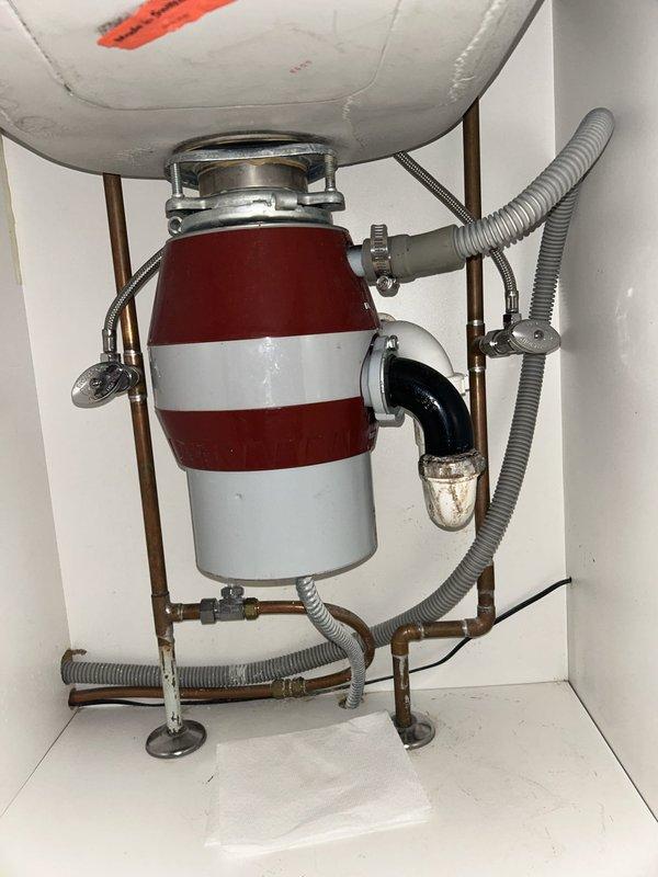 Responded to service call for leaking kitchen sink with suspected garbage disposal leak. Upon inspection, identified active leak originating from the garbage disposal's discharge connection and mounting assembly. Removed and inspected the existing garbage disposal unit, which displayed corrosion at the discharge elbow connection and compromised sealing at the sink flange mounting ring.

Disassembled the discharge plumbing assembly, including the P-trap and connecting drain lines. Replaced worn rubber gaskets and reinstalled discharge elbow with new stainless steel hardware and plumber's putty at all connection points. Resealed the sink flange mounting assembly with fresh plumber's putty and tightened the mounting ring to manufacturer specifications. Reconnected the P-trap assembly with new slip joint washers to ensure watertight connections throughout the drainage system.

Tested the garbage disposal operation and ran water through the system for several minutes to verify all connectio
