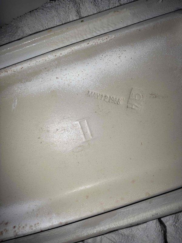 Responded to a recurring leak complaint at the toilet and inspected the tank, finding moisture streaking down the front of the tank and pooling at its base, with mineral deposits, rust residue, and heavy staining on the tank interior consistent with aged porcelain. Identified the tank as the source of the water loss and documented conditions with photos, with the aged tank (dated 1986) and fill/flush components indicated as the likely cause of the repeated leaking.