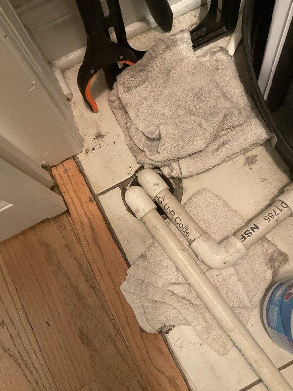 Responded to a reported water leak affecting the downstairs unit and inspected the HVAC condensate drain at the utility closet. Located the leak source at the clogged/non-draining condensate line, disconnected the PVC drain piping to access the floor drain, and cleared the obstruction to restore proper drainage. Absorbed standing water with towels and verified the area was clear of active leaking.