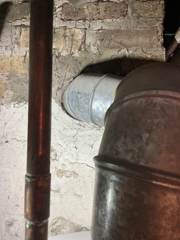 Inspected the water heater venting system following a home inspection report of carbon monoxide leakage and found the galvanized flue connector joint improperly sealed with torn, peeling foil tape over deteriorated insulation, allowing flue gas escape. Removed the compromised tape and insulation, then re-secured and properly sealed the vent connector joint and wall penetration to restore a gas-tight flue path. Verified the repair with a combustion and leak check to confirm no flue gas spillage.