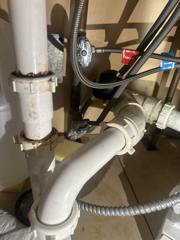 Removed the toilet and inspected the corroded brass closet flange and wax gasket, which were the source of the base leak, then reset the toilet with a new seal and addressed the tank leak. Evaluated the refrigerator ice and water supply line and the delayed hot water delivery at the fixtures, and inspected the under-sink supply stops, braided supply lines, and slip-joint drain connections, noting staining at the upper drain connection.