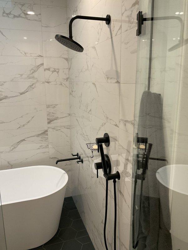Performed a water leak locate for a reported leak originating at the upstairs bathtub and migrating to the kitchen ceiling below. Inspected the tub, wall-mounted tub spout, shower valve trim, handheld sprayer connection, and surrounding tile surfaces, and documented the affected kitchen ceiling area with photos. Visible fixtures and tile appeared intact, so further diagnostics (such as pressure or flood testing of the tub drain and overflow, and valve inspection) are recommended to pinpoint the exact leak source.