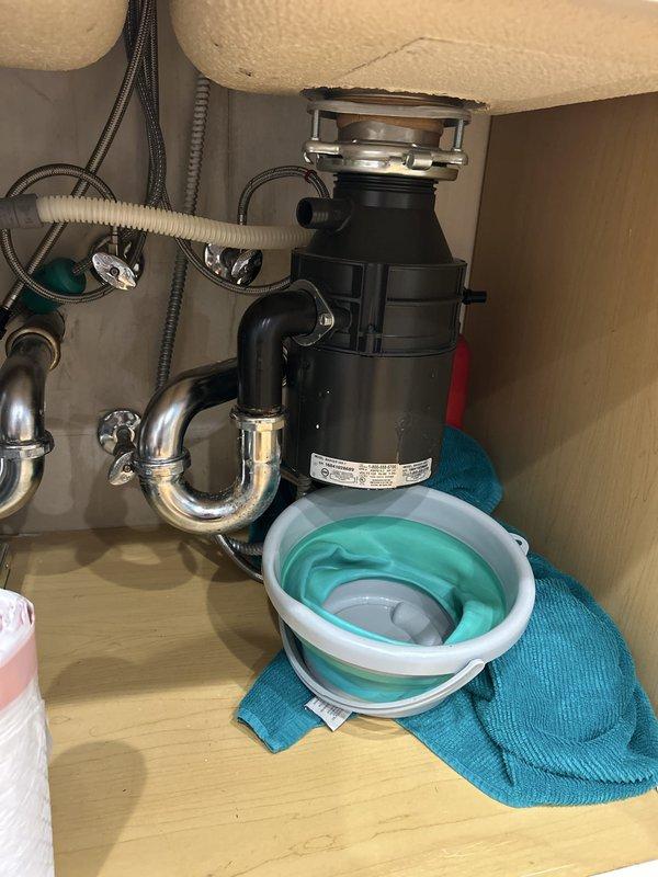 Installed a garbage disposal unit beneath the double-basin kitchen sink, securing it to the sink flange with the mounting ring and connecting the discharge outlet to the existing P-trap and drain line. Verified tight, leak-free connections at the trap, drain hose, and supply-line fittings, with no signs of corrosion or seepage. Work area was protected and left clean upon completion.