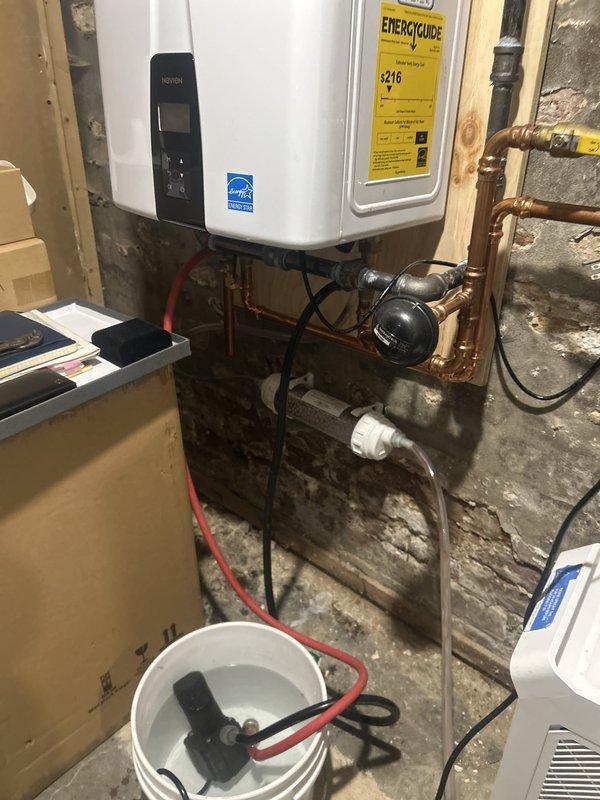 Performed annual maintenance on a Navien tankless water heater, including a full descaling flush using a submersible circulation pump, hoses, and isolation valves to remove mineral buildup from the heat exchanger. Inspected the copper piping, soldered joints, and expansion tank connections, and verified proper system operation after reconnecting.