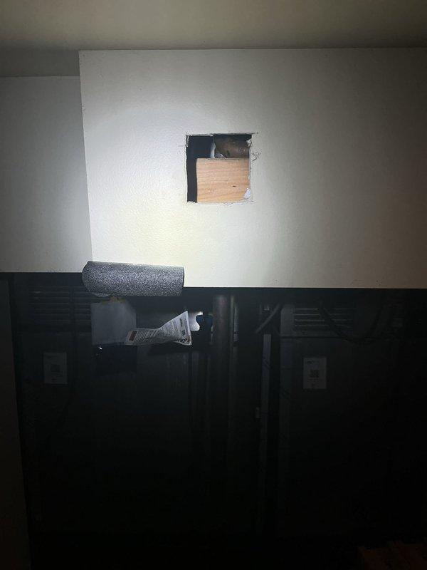 Responded to a recurring water leak originating at the bar area and migrating to the basement ceiling below, which had been previously serviced without lasting repair. Inspected the supply lines through an access opening in the wall, documented the pipe fittings and insulation condition, and noted extensive water staining, drywall deterioration, and peeling paint on the affected ceiling and soffit. Recommended follow-up repair of the identified leak source and restoration of the damaged drywall.