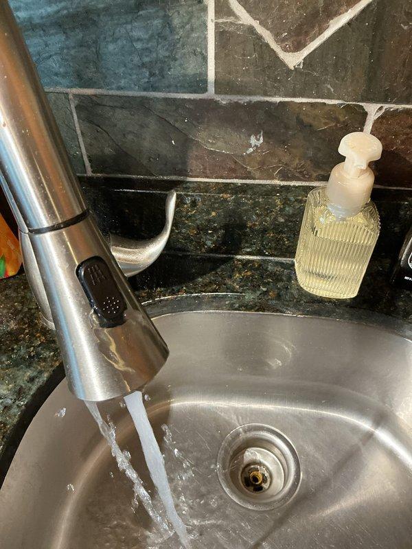 Responded to a kitchen faucet spraying water uncontrollably and diagnosed the failure in the pull-down faucet's spray head and hose assembly. Completed the repair and restored normal operation, and confirmed proper flow and spray-mode function with no leaks at the sink basin, with the faucet and surrounding fixtures left clean and in good condition.