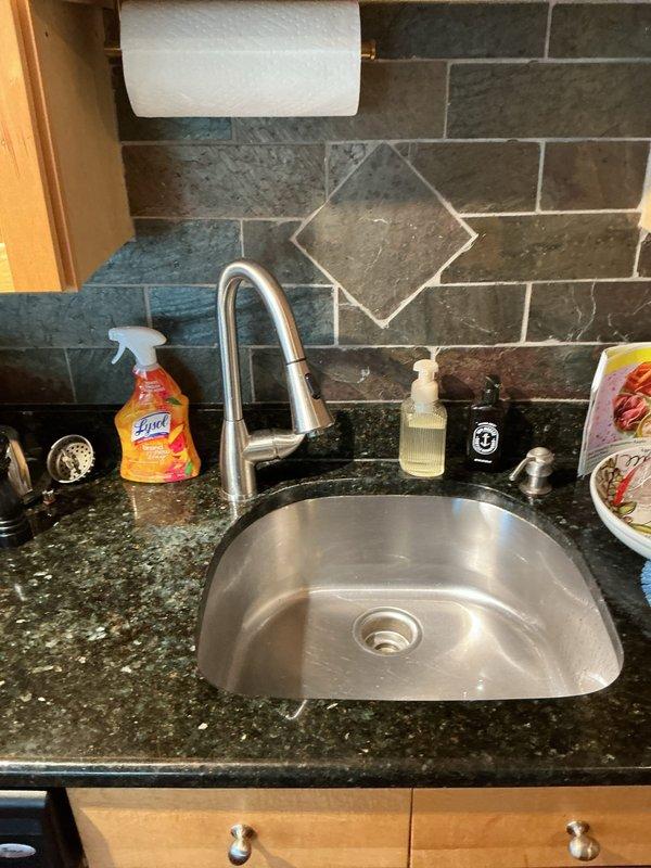 Responded to a kitchen faucet spraying water uncontrollably and diagnosed the failure in the pull-down faucet's spray head and hose assembly. Completed the repair and restored normal operation, and confirmed proper flow and spray-mode function with no leaks at the sink basin, with the faucet and surrounding fixtures left clean and in good condition.