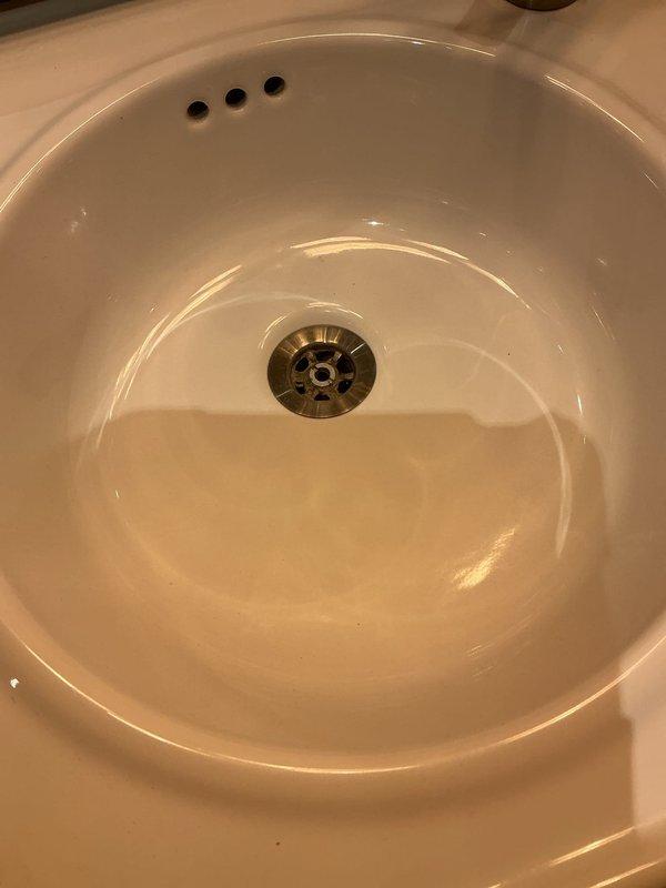 Responded to slow-draining bathroom sink and dishwasher drain complaints at a high-rise condominium unit, completing the required building access verification. Inspected the bathroom sink basin and drain strainer, and the drain was found clear with no standing water at completion, indicating flow was restored.