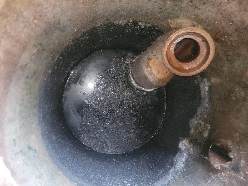 Inspected the shared grease trap serving six units and found heavy accumulation of grease, sludge, and sediment, along with significant corrosion on the inlet pipe stub and deteriorating concrete along the interior walls. Documented the condition with photographs and recommended pumping and cleaning of the trap, along with repair or replacement of the corroded inlet piping, to restore proper drainage and prevent recurring backups.