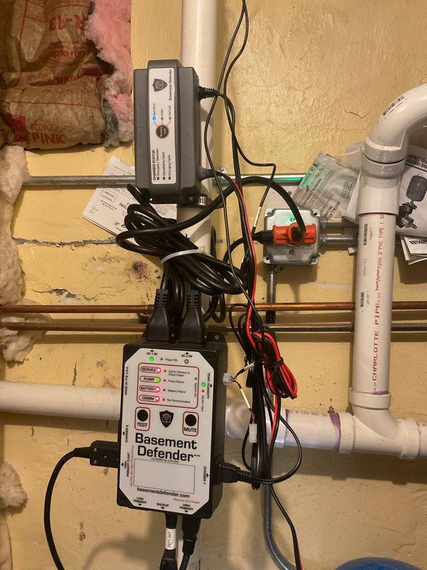 Performed an on-site estimate for replacement of the failed primary and battery backup sump pumps. Inspection of the sump pit found a corroded submersible pump and secondary pump or float assembly, sediment buildup, and a PVC discharge line with check valve, along with a Basement Defender backup control and charging system on the adjacent wall. Documented system conditions with photos and provided recommendations for pump replacement; no repairs were performed at this time per the customer's request.