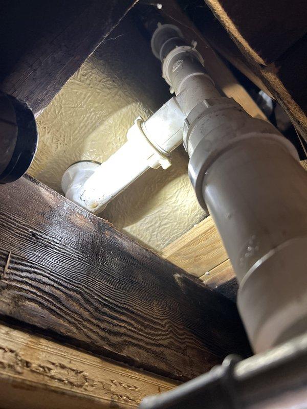 Performed a water leak locate, inspecting the bathtub overflow and drain assembly and tracing the associated drain piping beneath the floor, where the PVC drain line, trap, and fittings between the joists were examined. Water staining was observed on the adjacent framing, indicating a probable leak at the tub drain/overflow connections. Repairs were not started during this visit and will be completed on a follow-up visit.
