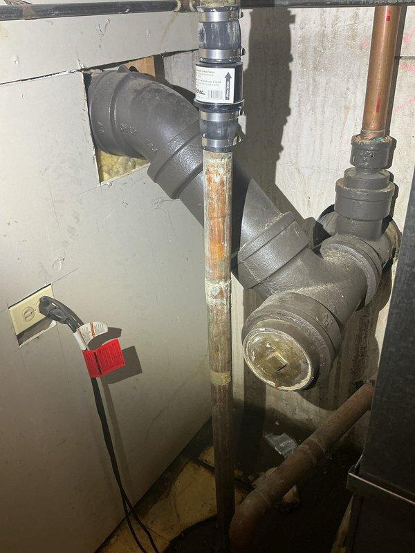 Inspected the sewer line and accessible cast-iron drain assembly, including the cleanout and check valve, and documented existing corrosion on the cleanout cap and adjacent piping. Evaluated the line and confirmed the need for hydro jetting; the line is scheduled for a return visit to complete hydro jet service.