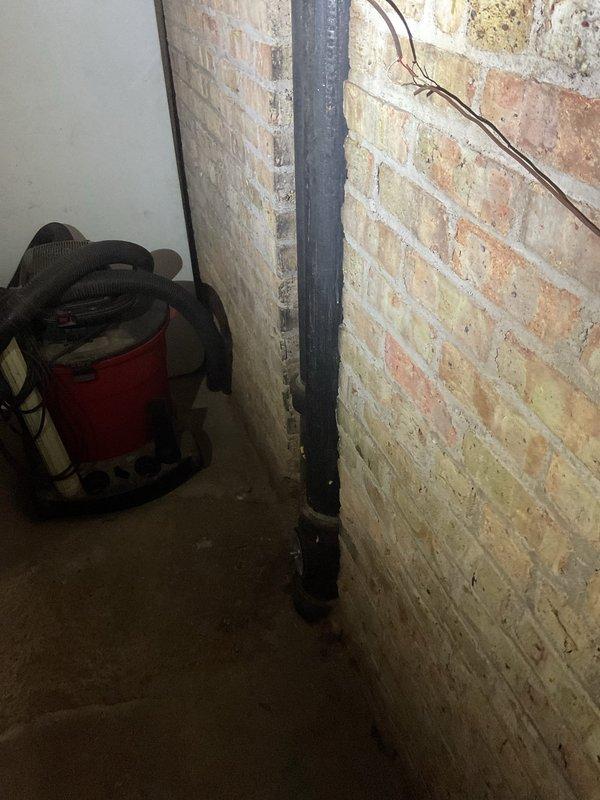 Responded to a warranty call regarding a suspected leak at a basement sanitary stack previously replaced. Inspected the cast-iron stack, clamp-style no-hub couplings, and adjacent drain piping, and documented existing conditions with photos, including heavy corrosion, staining, and soot on the surrounding piping and masonry, to support the warranty determination.